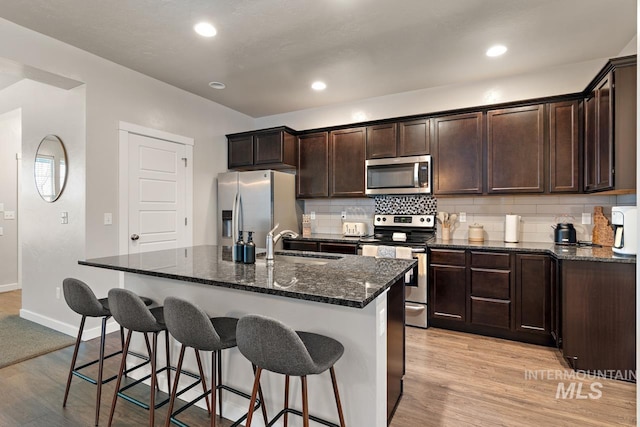 1873 W American Fork Dr, Meridian, ID 83642 - kitchen with stainless steel appliances, a sink, dark brown cabinets, a breakfast bar, and tasteful backsplash