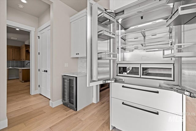 kitchen featuring white cabinetry, beverage cooler, light hardwood / wood-style floors, and decorative backsplash