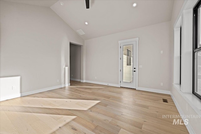 spare room featuring high vaulted ceiling and light hardwood / wood-style floors