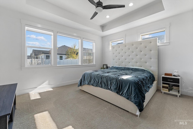 bedroom featuring a tray ceiling, carpet, multiple windows, and recessed lighting