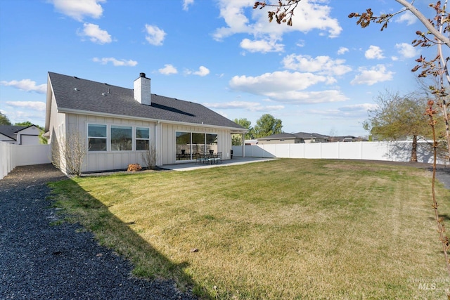 rear view of house with a chimney, board and batten siding, a patio area, and a fenced backyard