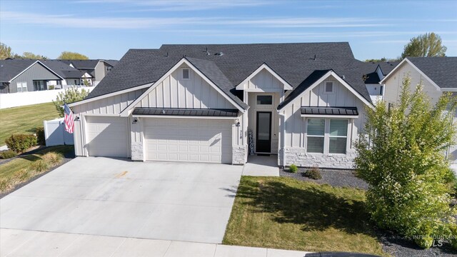 modern inspired farmhouse featuring concrete driveway, board and batten siding, stone siding, roof with shingles, and a garage