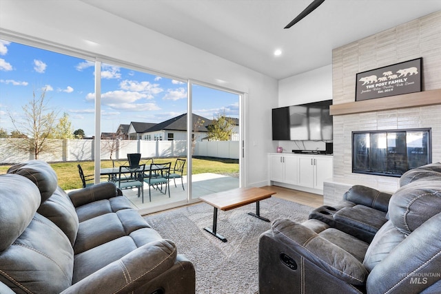 living area featuring a ceiling fan, light wood-type flooring, a tile fireplace, baseboards, and recessed lighting