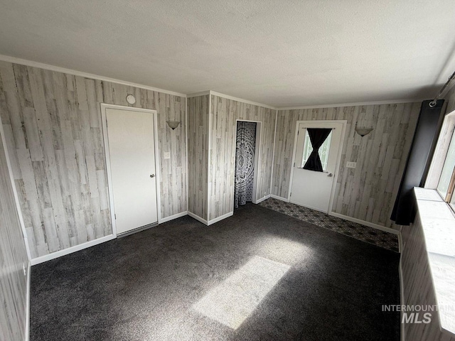 522 Ellis Ave, Winchester, ID 83555 - unfurnished bedroom featuring a textured ceiling, crown molding, wooden walls, carpet, and baseboards