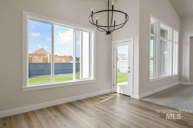 interior space with vaulted ceiling, an inviting chandelier, and light hardwood / wood-style flooring