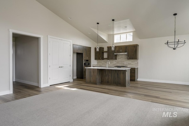 kitchen featuring dark hardwood / wood-style floors, a kitchen island with sink, sink, hanging light fixtures, and dark brown cabinetry