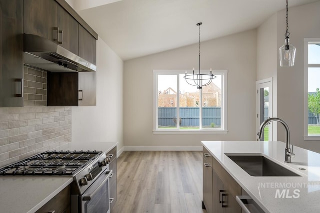 kitchen featuring light hardwood / wood-style floors, light stone countertops, stainless steel stove, lofted ceiling, and sink