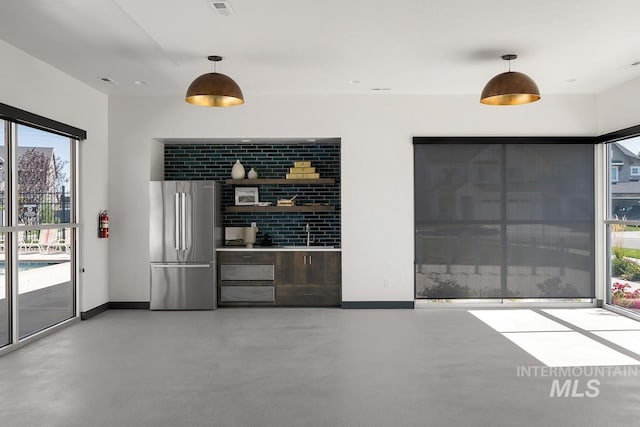 bar featuring sink, decorative light fixtures, and stainless steel refrigerator