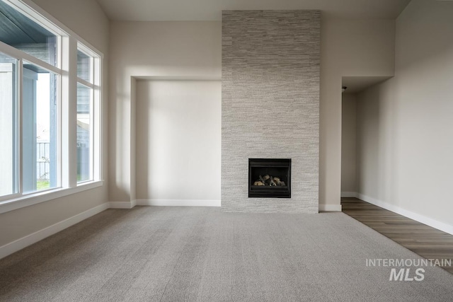 unfurnished living room with carpet flooring and a fireplace