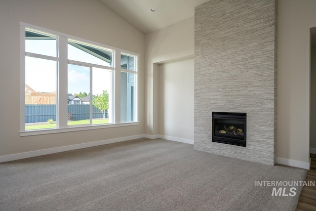 unfurnished living room featuring carpet, lofted ceiling, plenty of natural light, and a fireplace