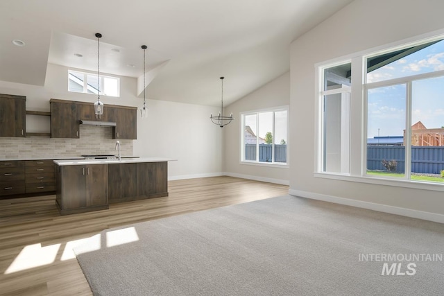 kitchen with dark brown cabinetry, an inviting chandelier, light wood-type flooring, and a kitchen island with sink