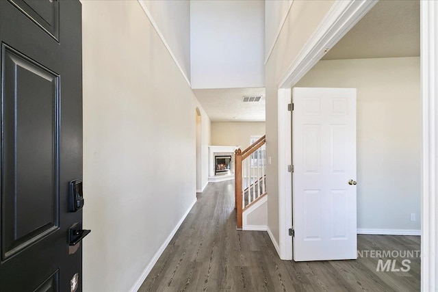 corridor featuring dark wood-style floors, stairs, visible vents, and baseboards