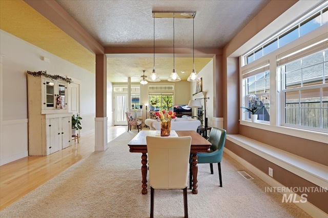 2260 N Eagle Creek Ln, Eagle, ID 83616 - carpeted dining room featuring plenty of natural light, wainscoting, a textured ceiling, and wood finished floors