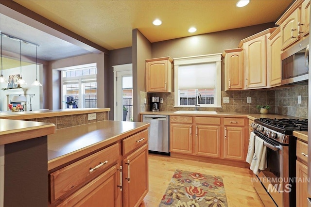 2260 N Eagle Creek Ln, Eagle, ID 83616 - kitchen with appliances with stainless steel finishes, a sink, light wood finished floors, backsplash, and light brown cabinetry