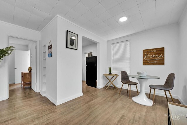 dining area with baseboards, wood finished floors, and crown molding