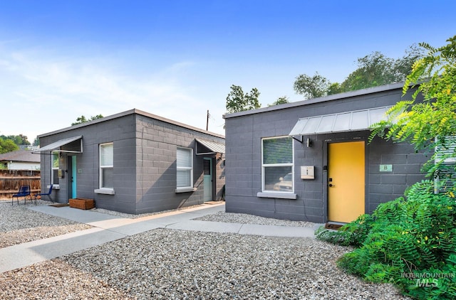 contemporary home featuring concrete block siding and fence