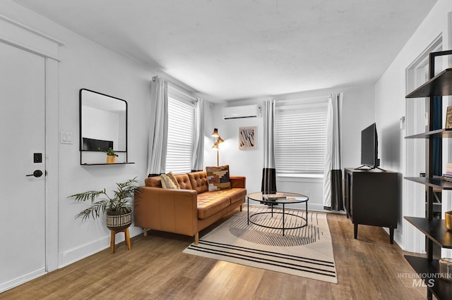 living area featuring baseboards, dark wood-style flooring, and a wall mounted AC