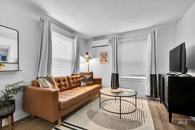 living area with light wood-style flooring, baseboards, and an AC wall unit