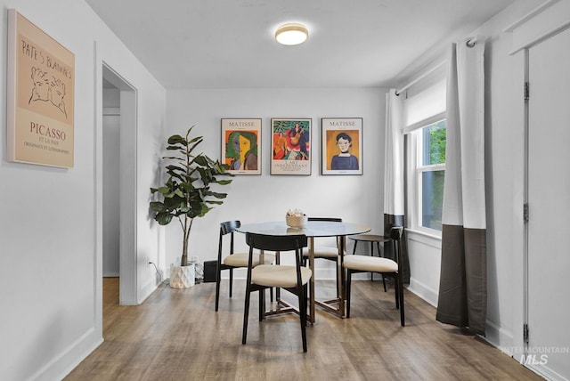 dining space with baseboards and wood finished floors