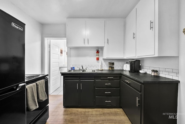 kitchen with dark cabinets, a sink, white cabinets, black appliances, and dark countertops