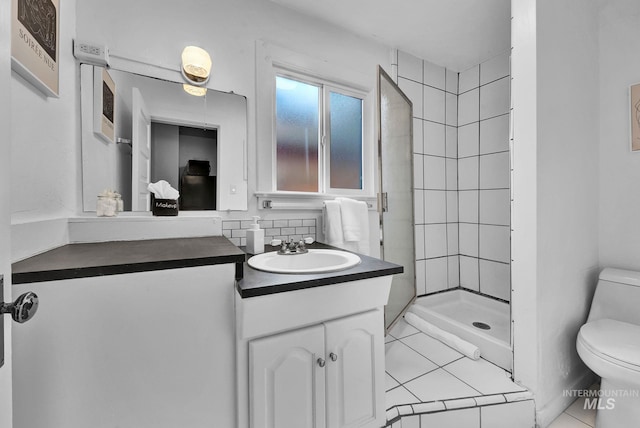 bathroom featuring toilet, a shower stall, tile patterned flooring, and vanity