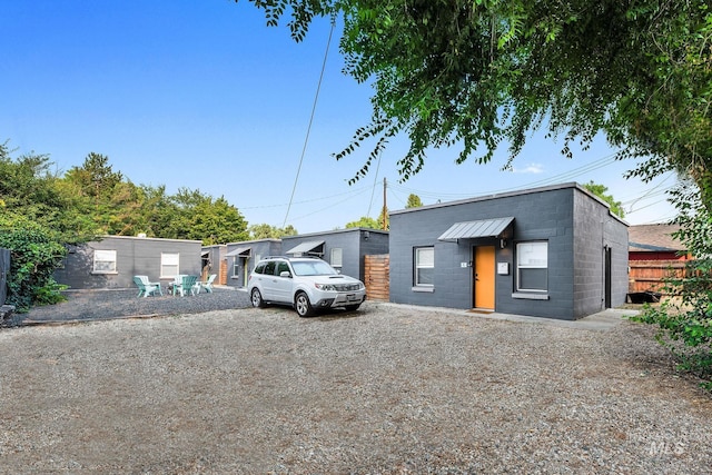 view of front of property with concrete block siding, driveway, and fence