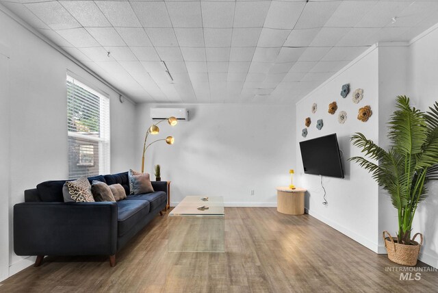 living room featuring baseboards, ornamental molding, an AC wall unit, and wood finished floors