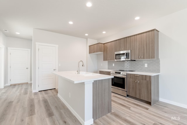 4435 N Magical Creek Ave, Meridian, ID 83646 - kitchen with light countertops, a sink, light wood-style floors, a center island with sink, and stainless steel appliances