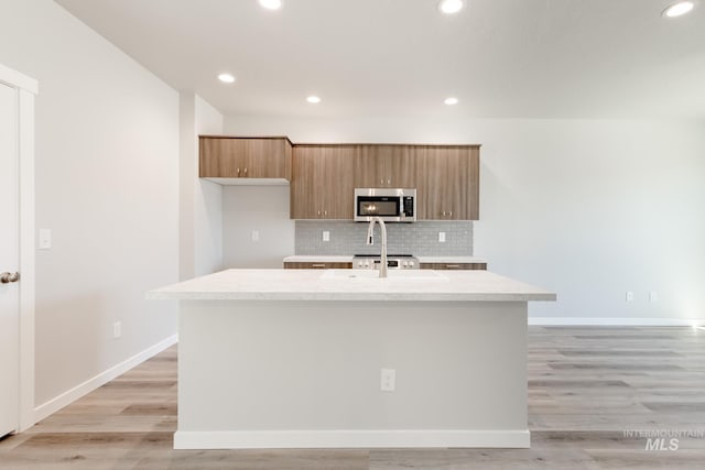 4435 N Magical Creek Ave, Meridian, ID 83646 - kitchen with a kitchen island with sink, stainless steel microwave, backsplash, light countertops, and recessed lighting