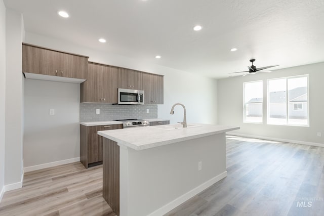 4435 N Magical Creek Ave, Meridian, ID 83646 - kitchen featuring light wood finished floors, a sink, stainless steel appliances, light countertops, and tasteful backsplash