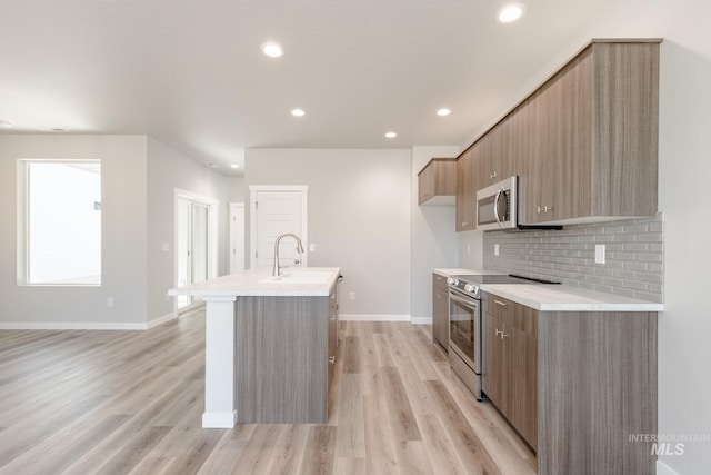 4435 N Magical Creek Ave, Meridian, ID 83646 - kitchen featuring stainless steel appliances, light wood-type flooring, a kitchen island with sink, baseboards, and modern cabinets