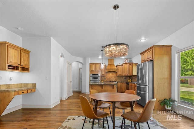 6370 E Escarpment Ct, Boise, ID 83716 - dining room featuring arched walkways, light wood-type flooring, a chandelier, baseboards, and recessed lighting
