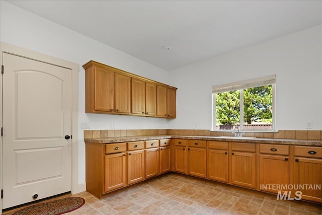 6370 E Escarpment Ct, Boise, ID 83716 - kitchen with brown cabinetry, a sink, and stone finish floors