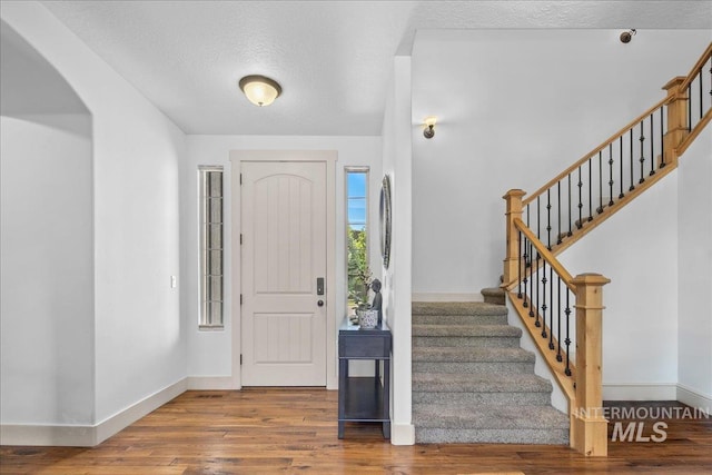 6370 E Escarpment Ct, Boise, ID 83716 - entrance foyer with arched walkways, baseboards, wood finished floors, stairway, and a textured ceiling