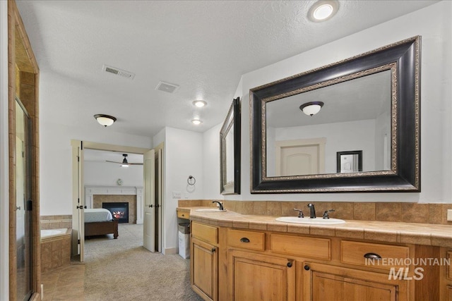 6370 E Escarpment Ct, Boise, ID 83716 - ensuite bathroom featuring double vanity, a glass covered fireplace, a shower with shower door, ceiling fan, and a textured ceiling