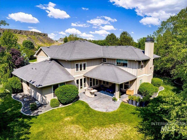 6370 E Escarpment Ct, Boise, ID 83716 - rear view of house featuring a patio area, a chimney, a yard, roof with shingles, and a garage