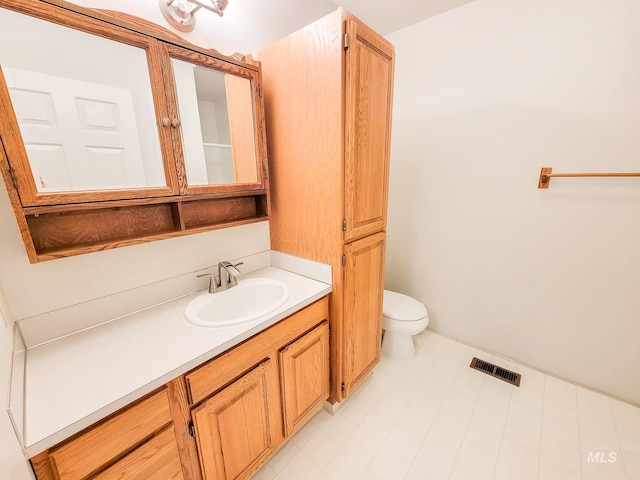 bathroom with vanity, toilet, and visible vents