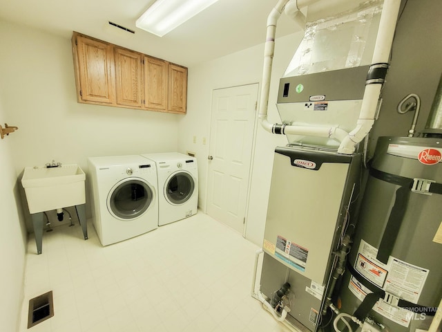 washroom featuring strapped water heater, light floors, visible vents, cabinet space, and washer and clothes dryer