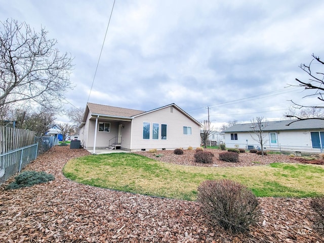 rear view of house featuring fence and a lawn