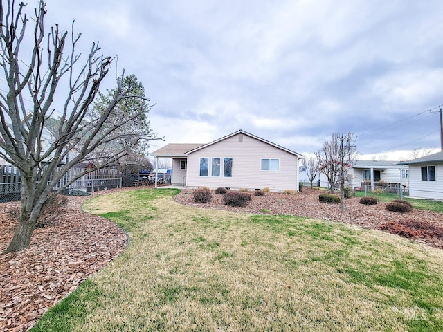 back of property featuring a lawn and fence