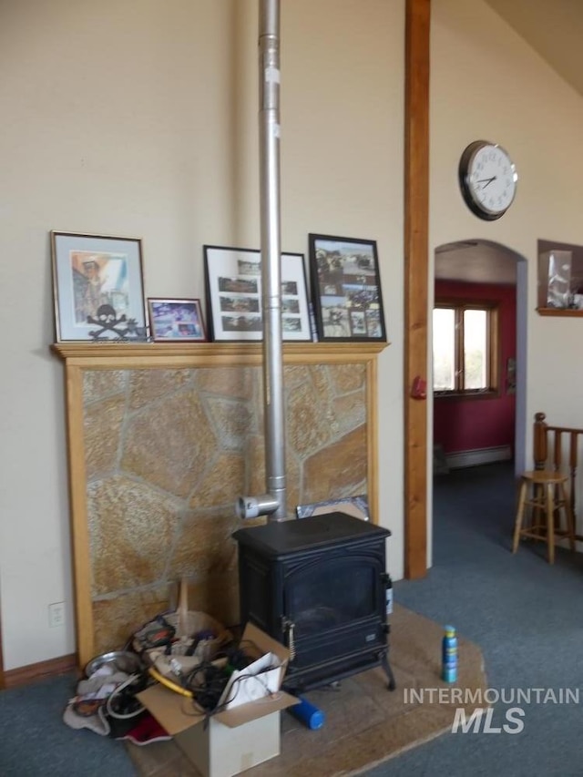 room details with arched walkways, carpet floors, baseboard heating, and a wood stove