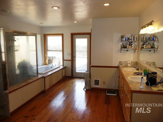 full bath with a wainscoted wall, recessed lighting, wood-type flooring, visible vents, and a sink