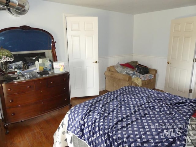 bedroom featuring wainscoting and wood finished floors