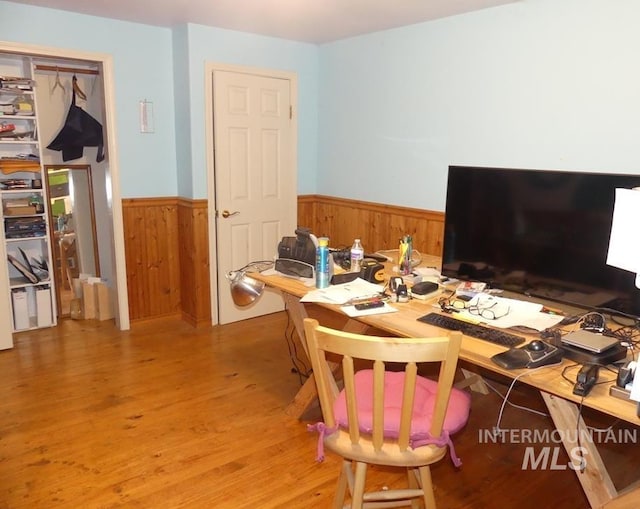 home office featuring a wainscoted wall, light wood finished floors, and wood walls