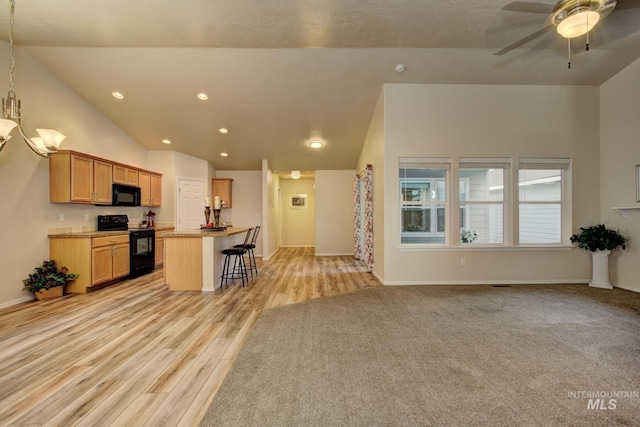 kitchen with a breakfast bar, ceiling fan, black appliances, open floor plan, and a center island