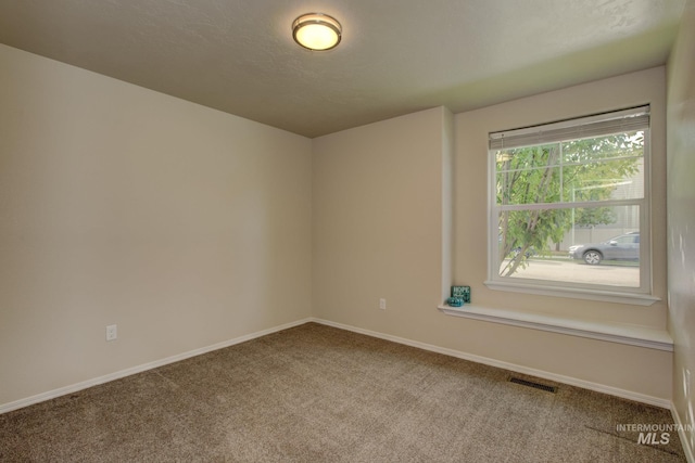 empty room with baseboards, visible vents, carpet floors, and a textured ceiling