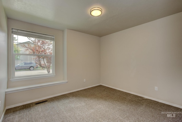 spare room featuring carpet flooring, baseboards, and visible vents