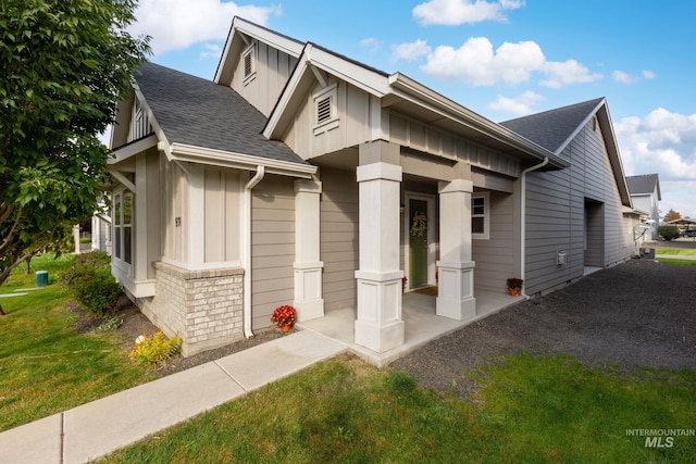 view of front of property featuring board and batten siding, a front lawn, and roof with shingles