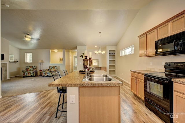 kitchen featuring a wealth of natural light, open floor plan, black appliances, and a sink