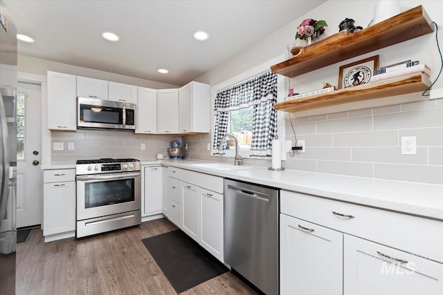 kitchen with light countertops, stainless steel appliances, white cabinetry, a sink, and dark wood-style floors